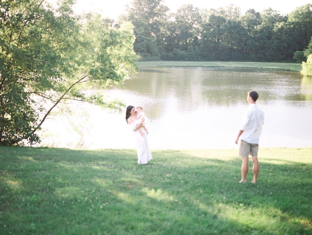 mom holding baby girl while dad admires from afar