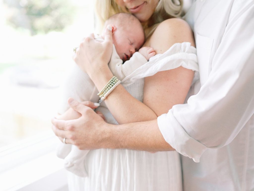 Mom and dad cuddle newborn during in home newborn session