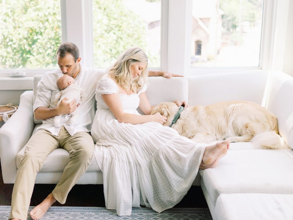 Family cuddles with dog on couch holding baby during Franklin in home newborn session 