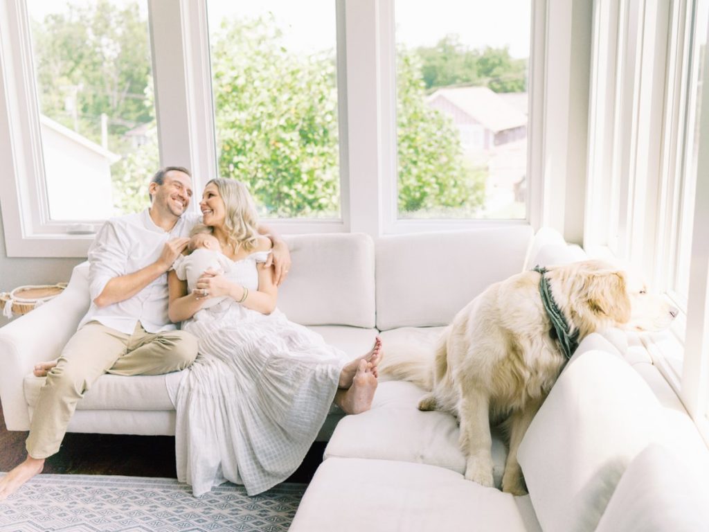 Mom, dad, baby, and dog on couch during in home newborn session