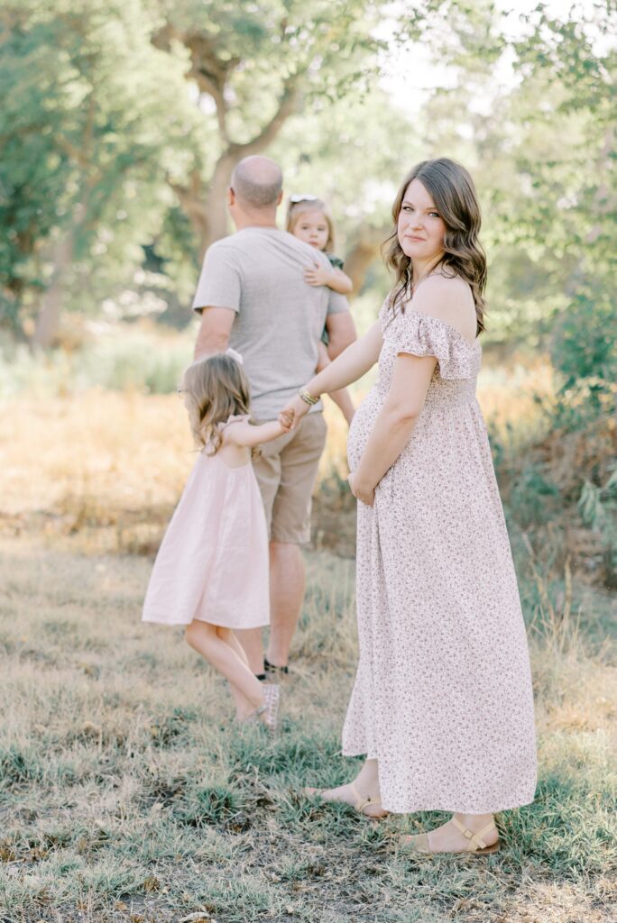 Pregnant mom walking behind family during nashville outdoor maternity session