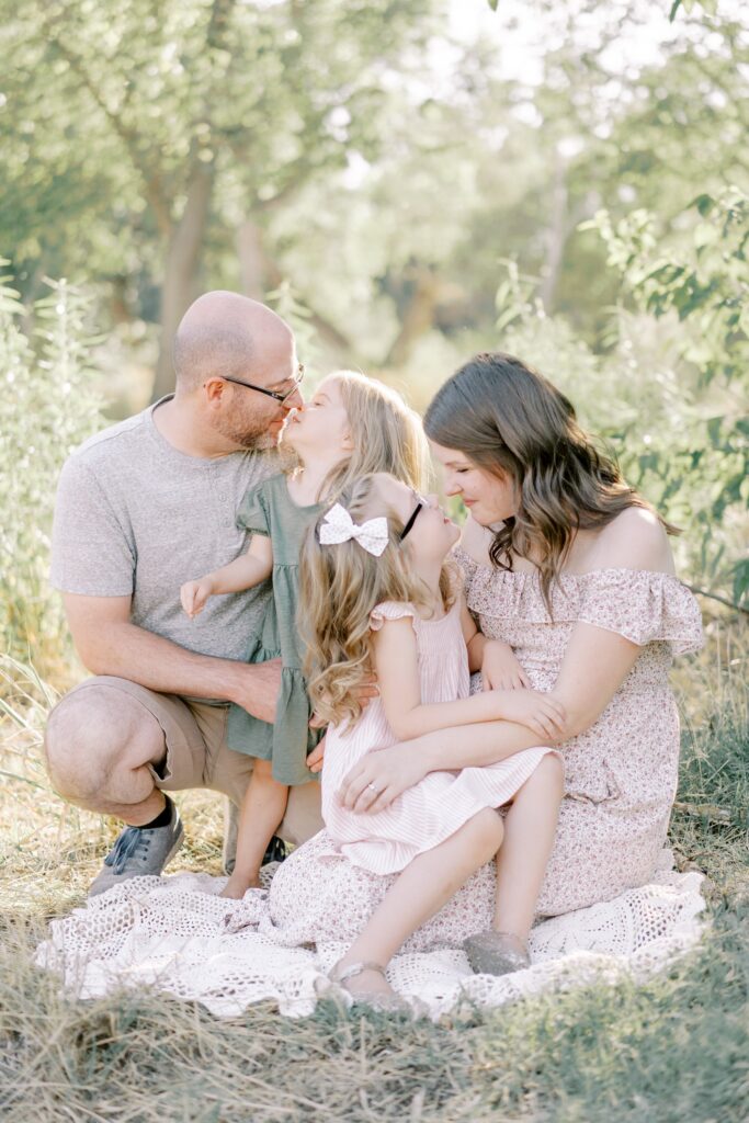 Both mom and dad give eskimo kisses to their daughters during this nashville outdoor maternity session