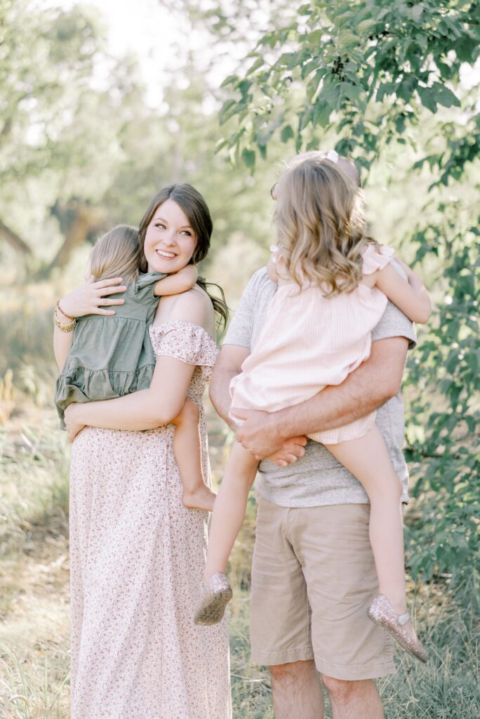 Mom and dad both holding and cuddling daughter during this nashville outdoor maternity session