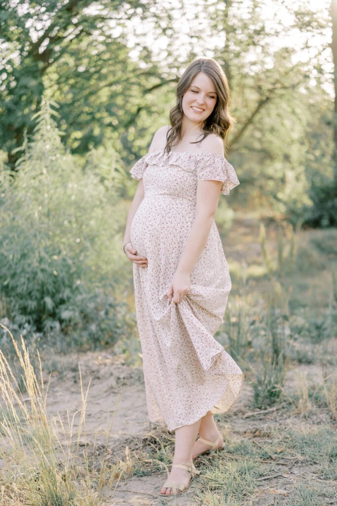 An expecting mother twirling her dress with one hand and holding her bump with her other hand
