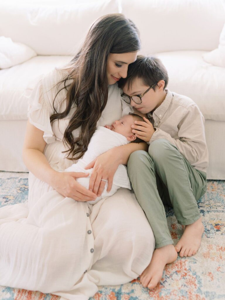 Courtney Houk Photography takes a photo of mom cuddling newborn baby boy with oldest brother snuggled in her arms