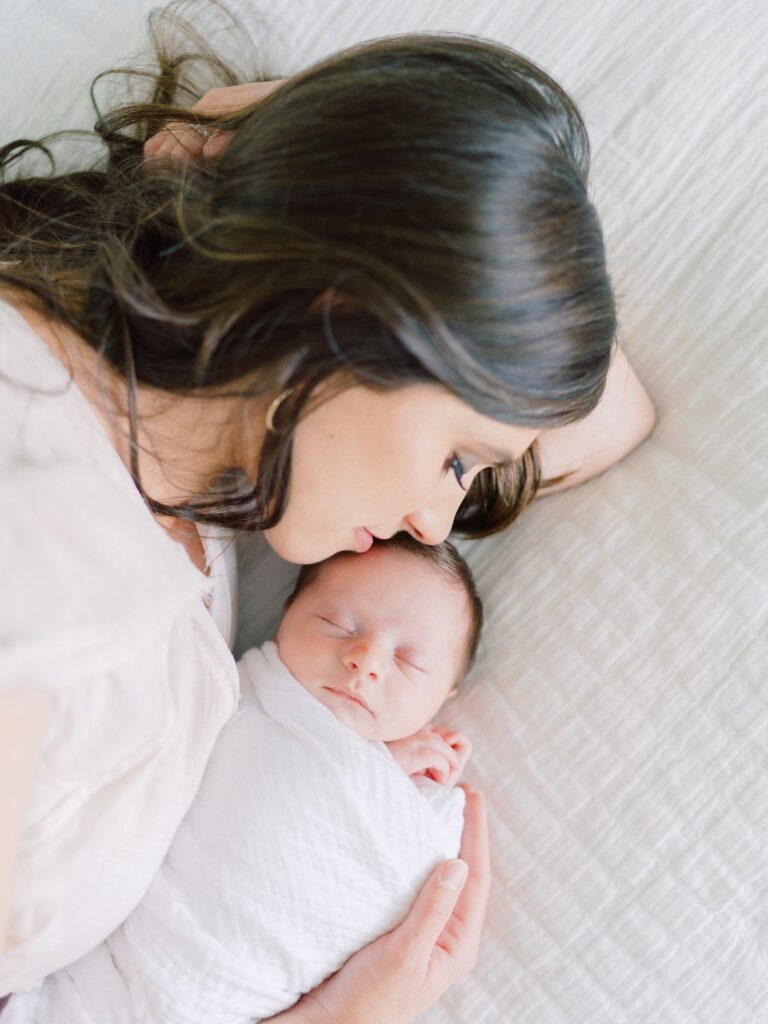 Nashville newborn photographer Courtney Houk captures a photo of mom laying on bed cuddling her 5th baby boy