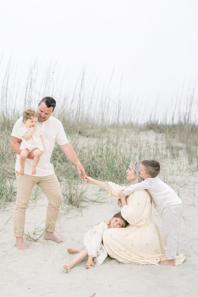 A family of five on the beach wearing neutral colors for their family photos