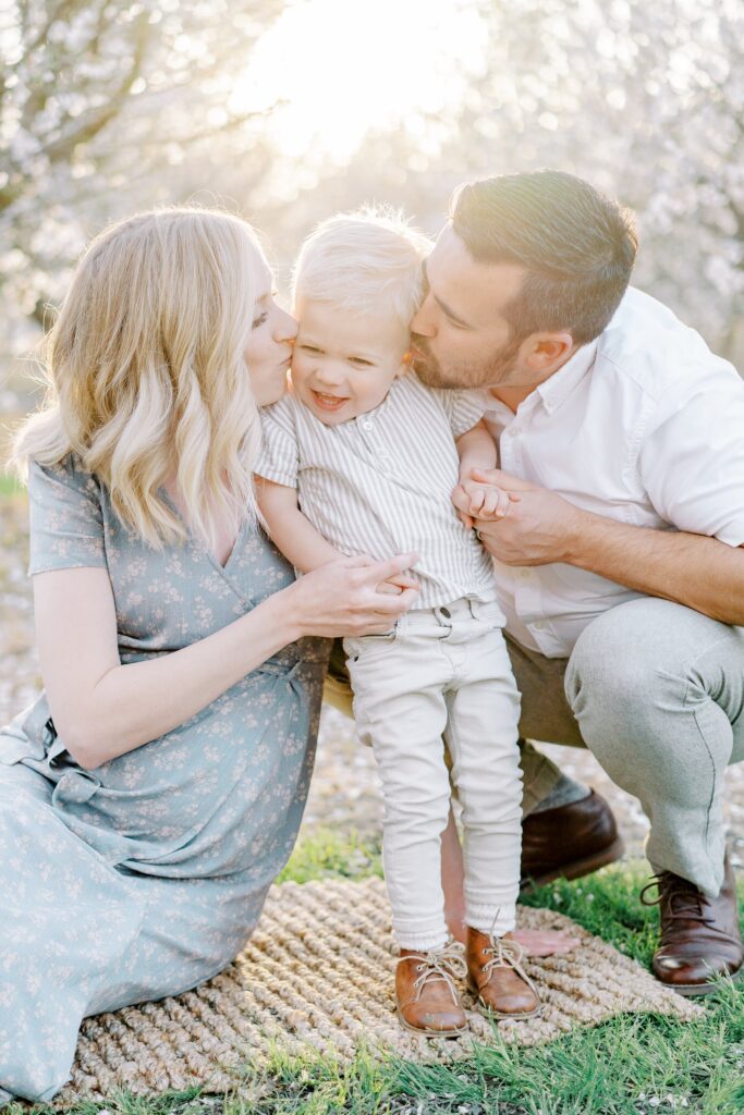 A mom and dad sit on each side of their son and kiss his cheeks in the Nashville family session by photographer Courtney Houk