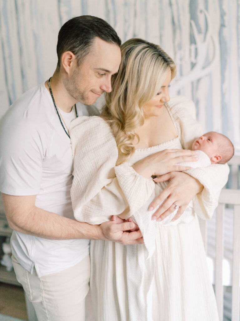 A first time dad admires his newborn baby boy as his wife cradles her son