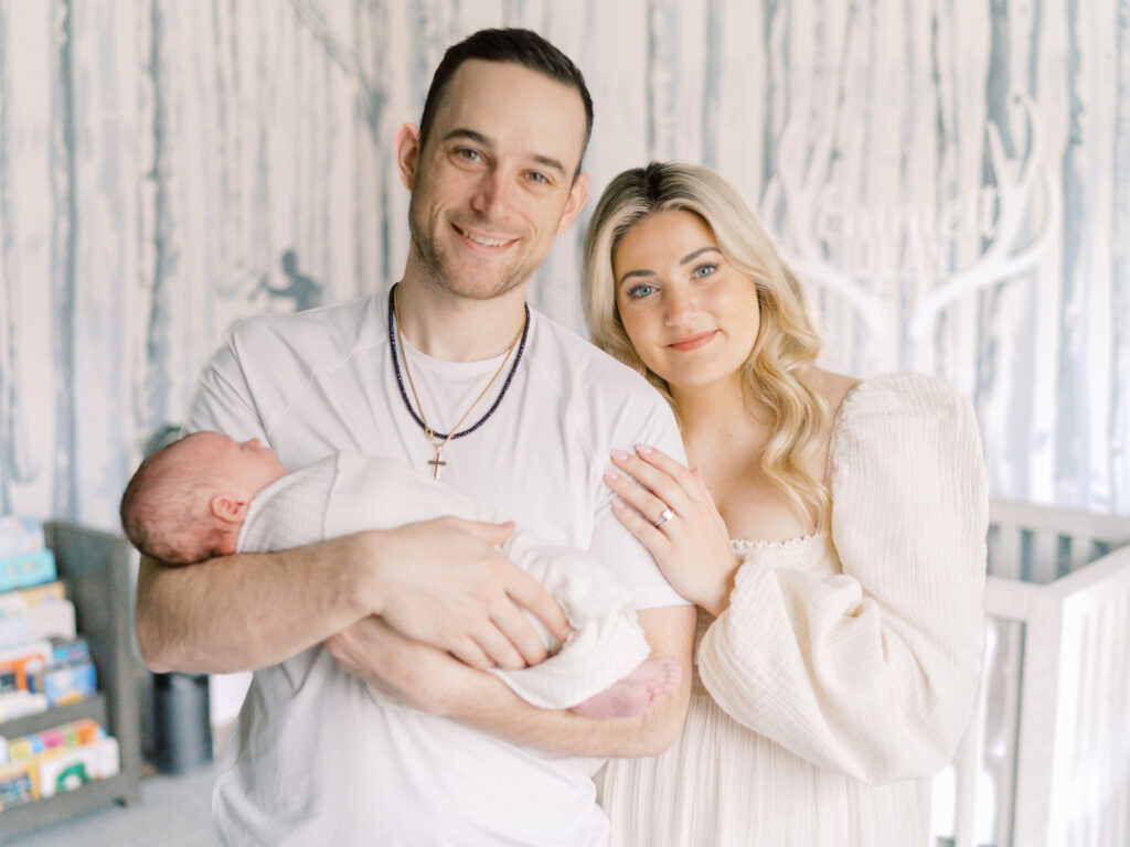 College Grove TN newborn photographer Courtney Houk captures a smiling portrait of a dad holding his newborn son and mom leaning on dad's shoulder