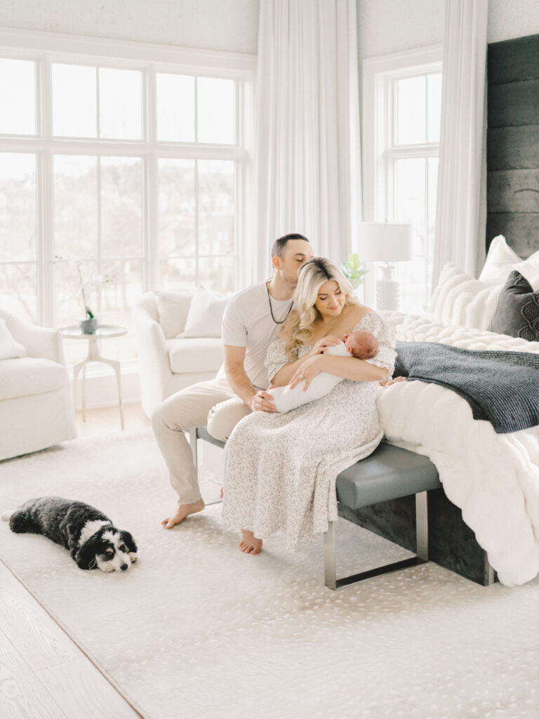 A father kisses his wife on the head as she holds their newborn baby boy