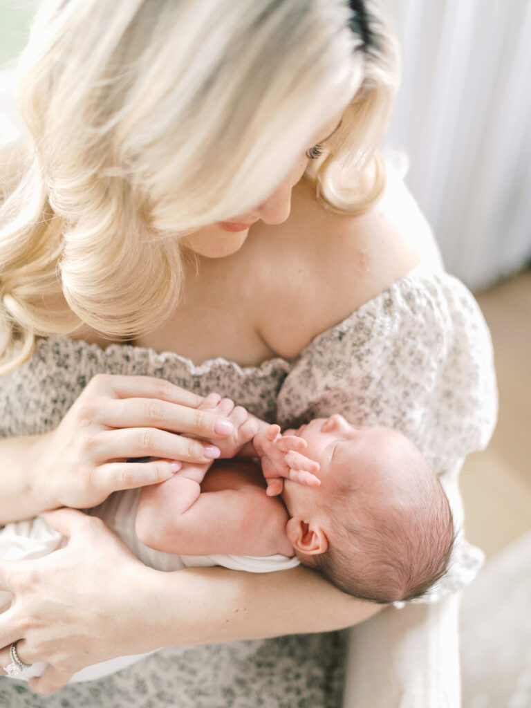 A first time mother cradles her baby boy and holds his hand