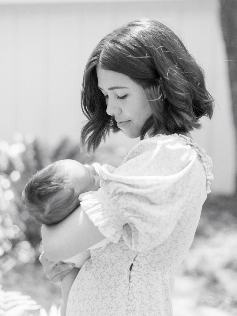 This black and white image captures a mama looking down at her baby boy while she cradles him