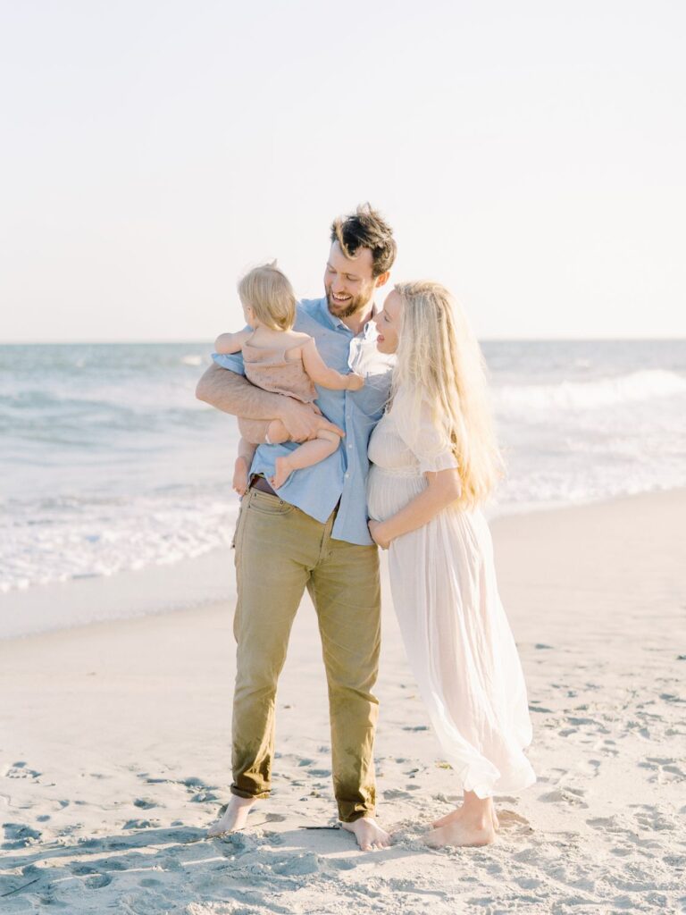 a man and woman holding a baby on a beach