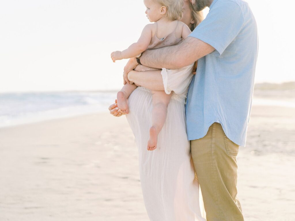 a man and woman holding a baby on a beach