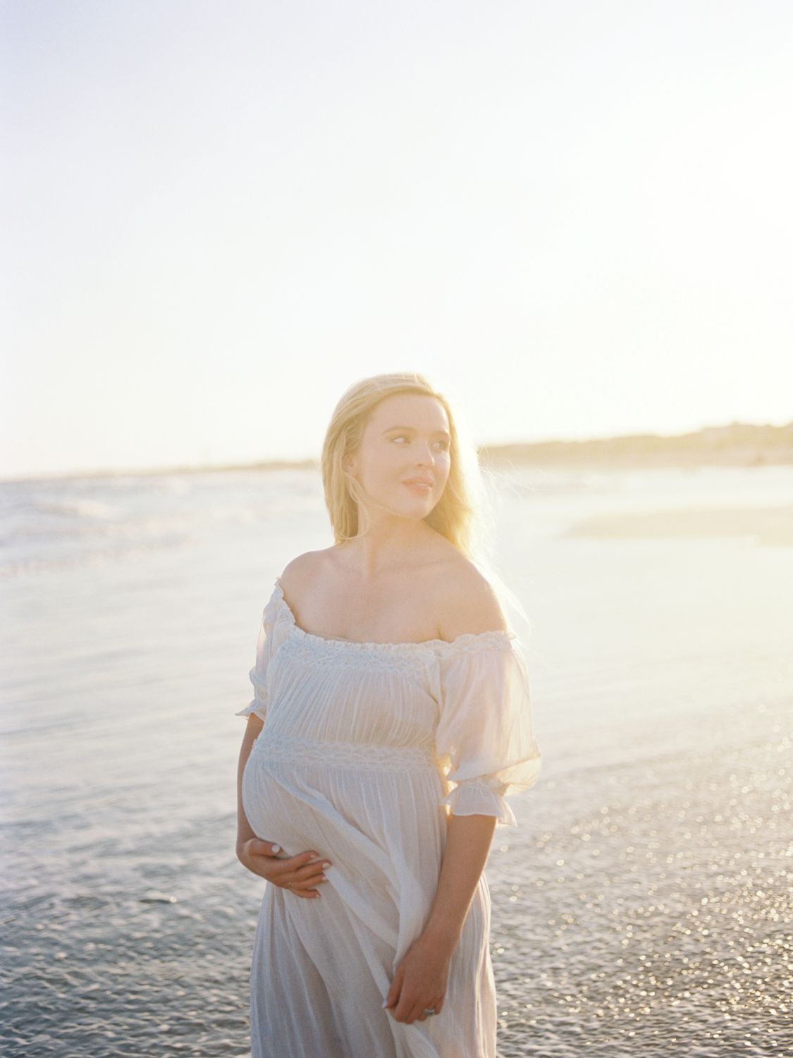 a pregnant woman standing on a beach