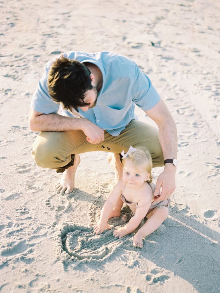 a man and a baby playing in the sand