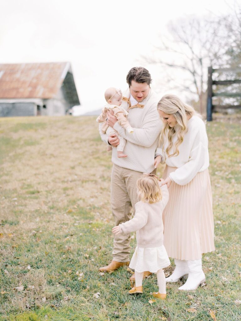 a dad and mama with their two daughters in a wintery grassy field